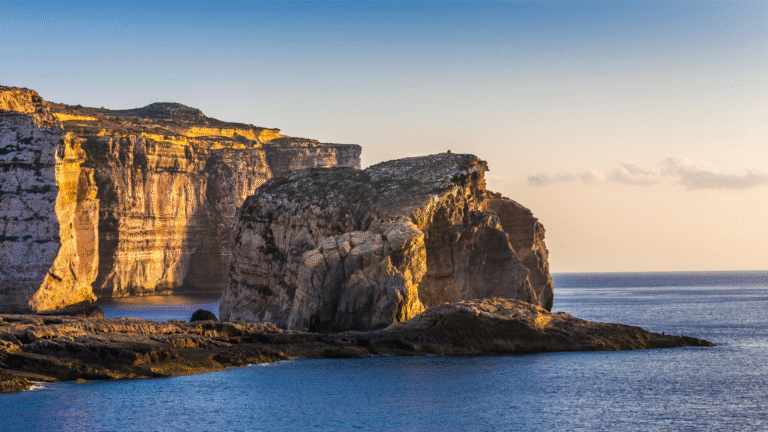 Fungus Rock, Dwerja Bay, Gozo. An islet set against sheer limestone cliffs.