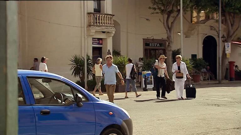 Two men, dressed in short sleeve shirts, have a conversation by a hotel pool