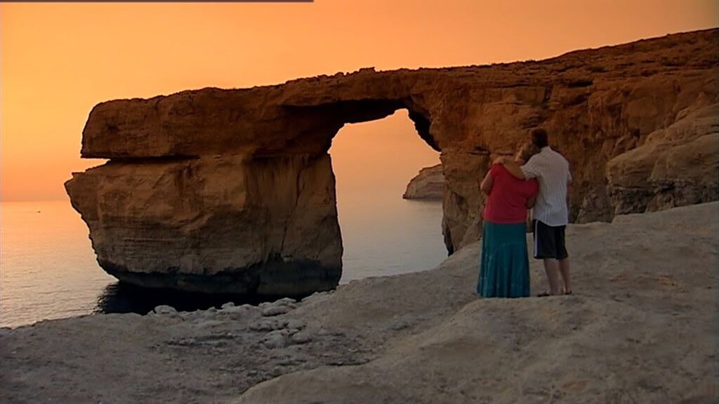 Steve McDonald and Eileen Grimsby stand by the Azure Window at sunset.