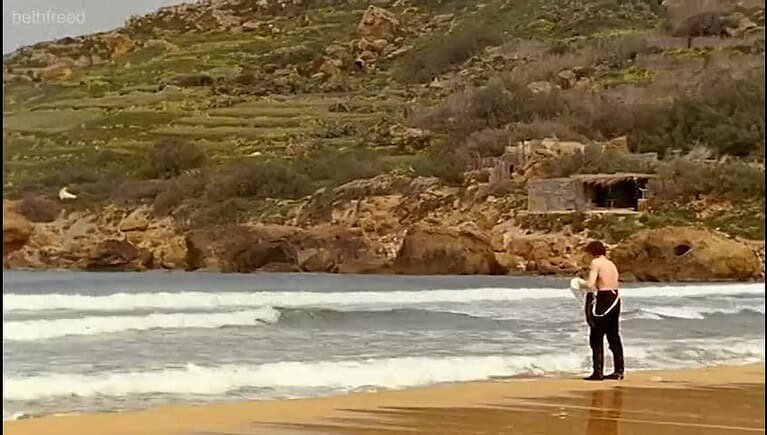 A group of men stand on the sea shore.