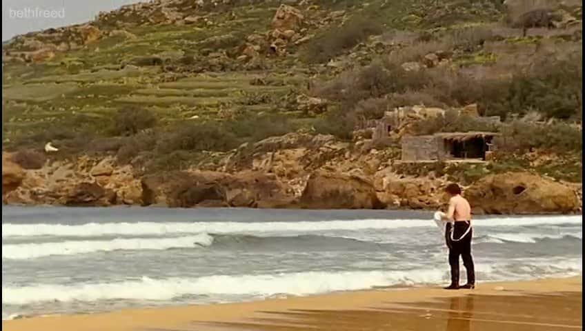 A group of men stand on the sea shore.