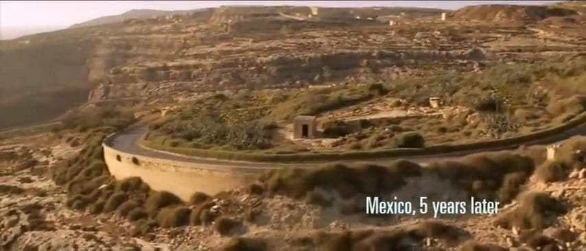 A car drives down a winding road towards the sea.