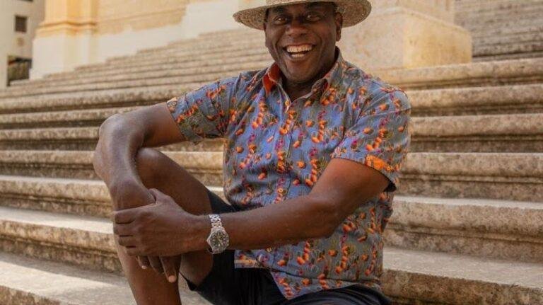 Ainsley Harriott sitting on stone steps.