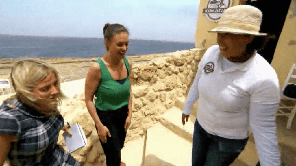 Three women stand outside the Gozo Sea Salt shop, Xwejni Bay.