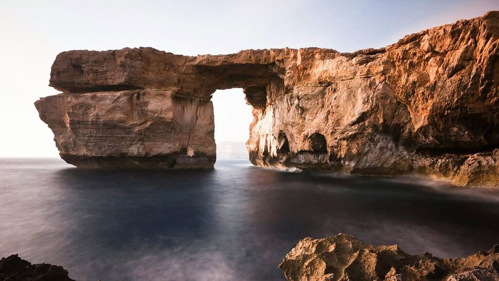 Rocky arch over tranquil sea.