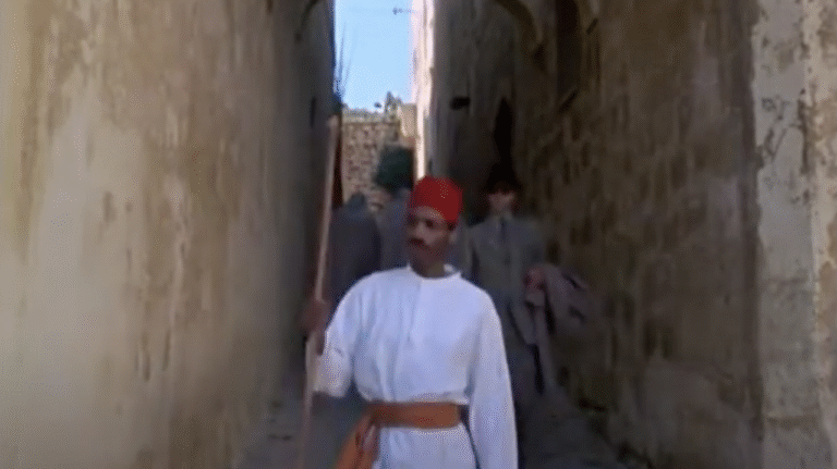 A man dressed in traditional Moroccan garb in a narrow passage.