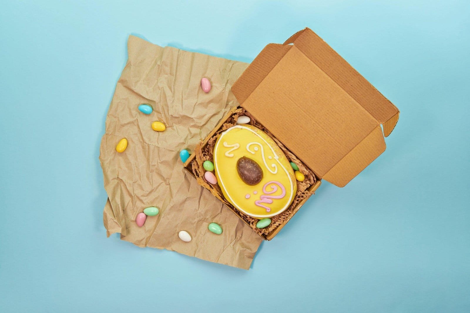 Traditional Maltese Figolli, shaped like an Easter egg, in a box on wrinkled brown paper bag.
