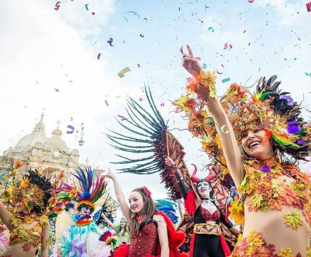 Several woman in colourful carnival dancer outfits.