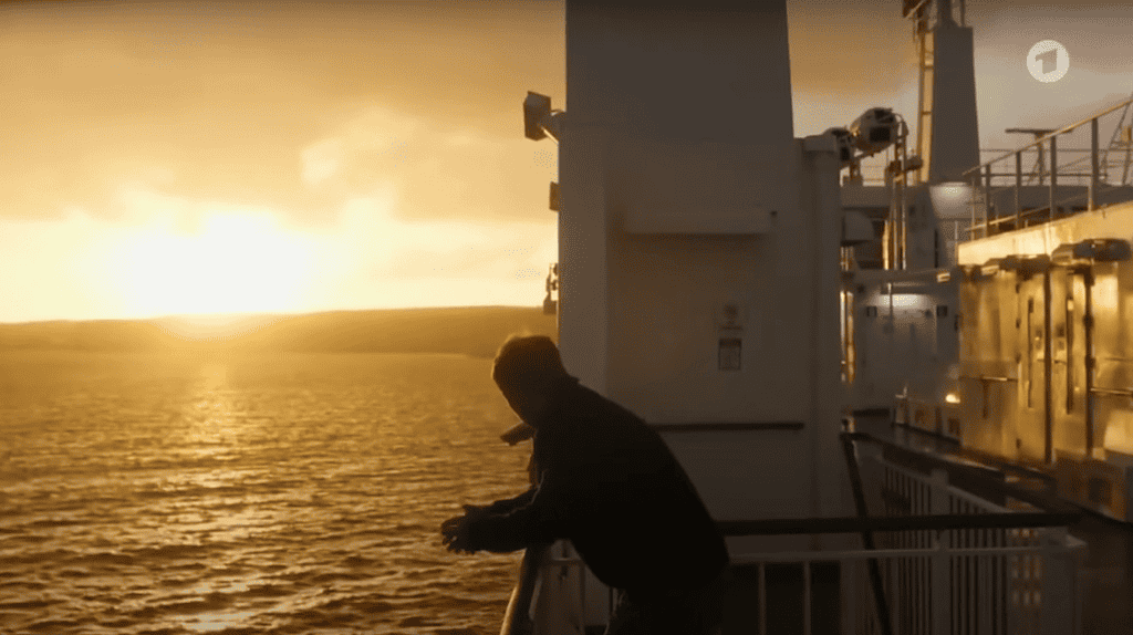 Matthias Koeberlin, as Hartwig Seeler, leans over the railing of the Gozo Channel Ferry.