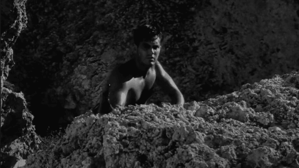 Signalman Andrew Brown (Jeffrey Hunter) shelters on a cliff in Sailor of the King.