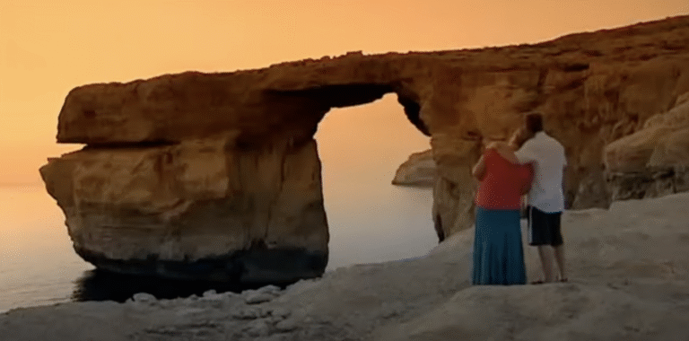 Steve McDonald and Eileen Grimsby stand by the Azure Window at sunset.