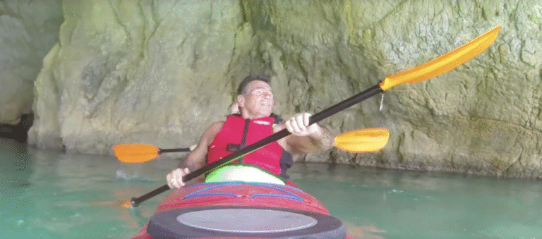 Two men in a red tandem kayak in a limestone cave.