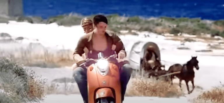 A man and woman on a scooter being followed by a horse and cart.