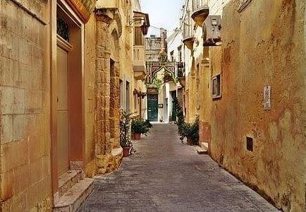 Narrow, cobbled lane, leads between traditional Gozitan houses.