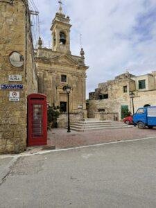 Mediterranean village square with a red telephone box.