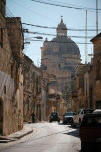 Village street in Gozo, Malta with the Rotunda of St John's the Baptist church in the background.