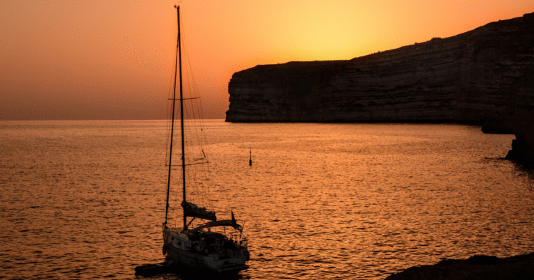 A sailboat in the water at sunset.