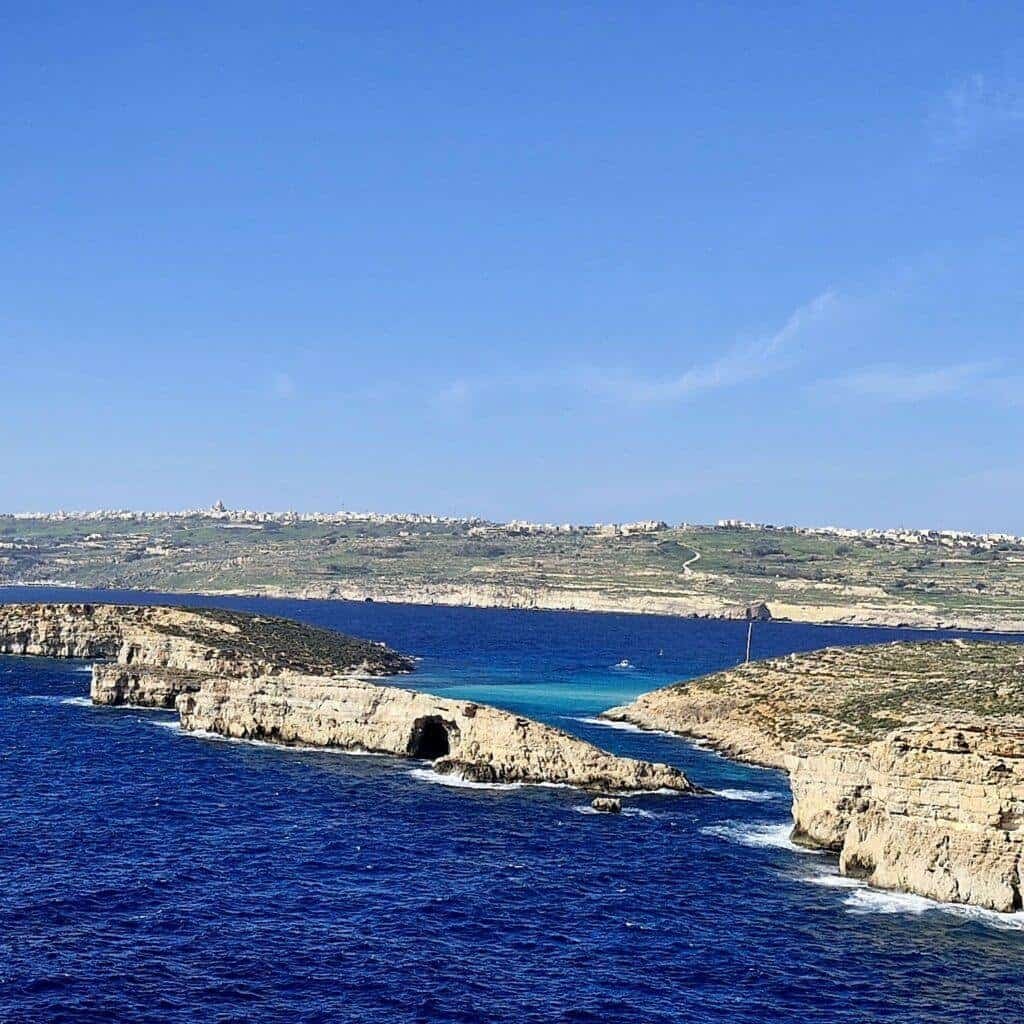 A dark blue sea dotted with limestone islets and rocks.