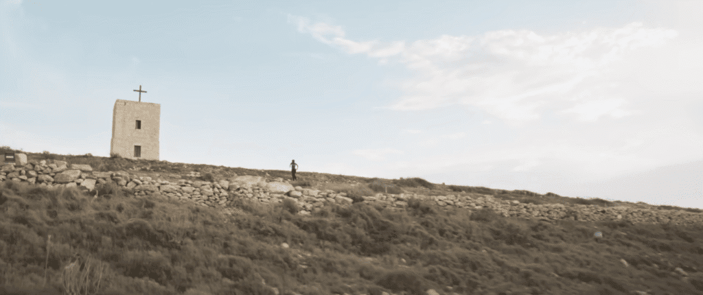 A limestone tower with a rough wooden cross on the roof.
