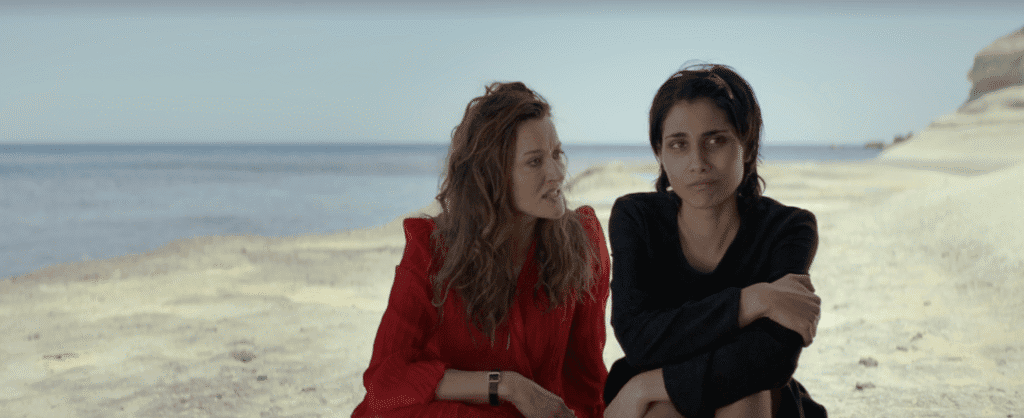- Women sitting on Gozo beach at sunset, enjoying the island's scenic beauty and tranquility.