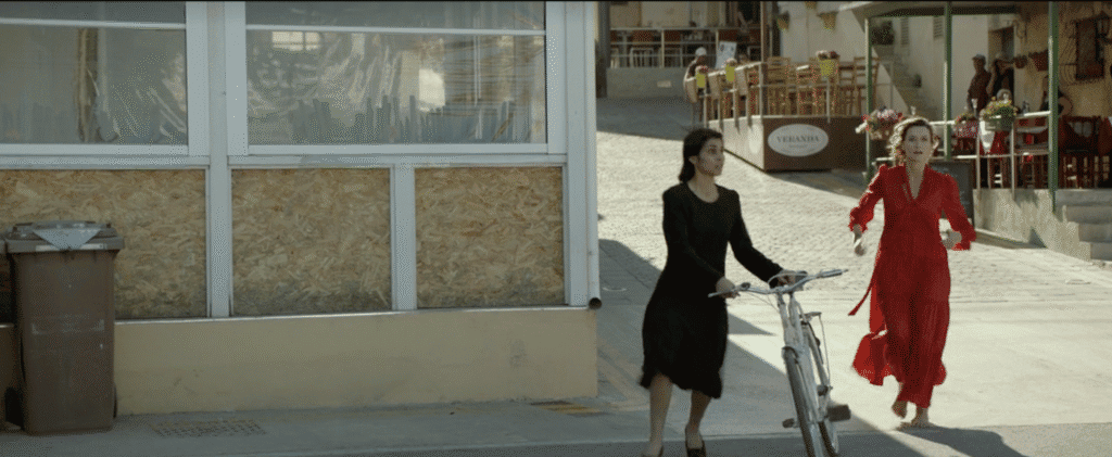 A young woman wearing a black dress pushes a white bicycle.