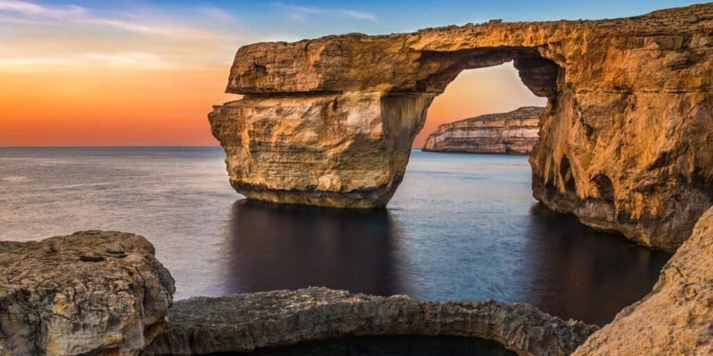 Natural rock arch over tranquil sea.