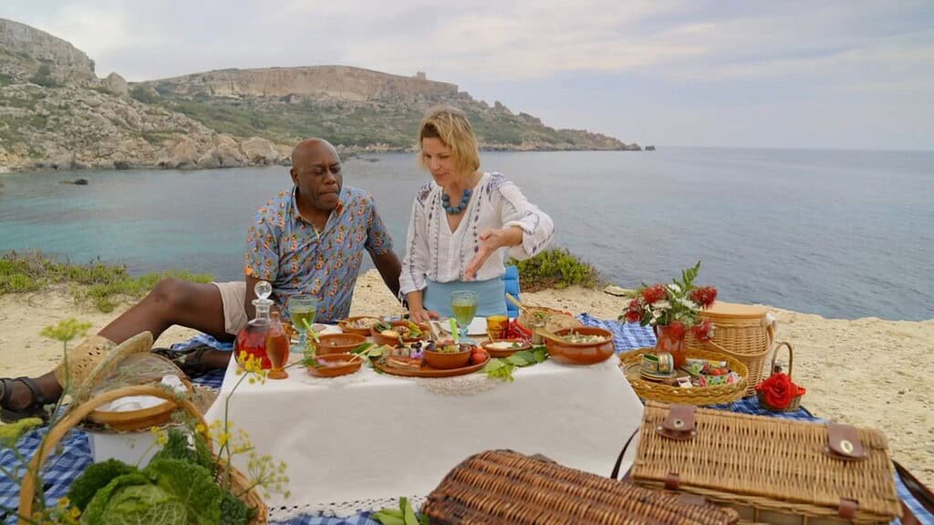 Vibrant picnic on a Gozo beach with local food and scenic coastal views.