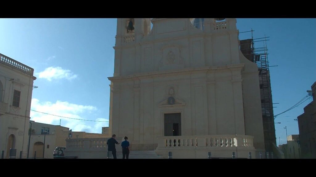 A man and woman walk up the steps outside a large church.