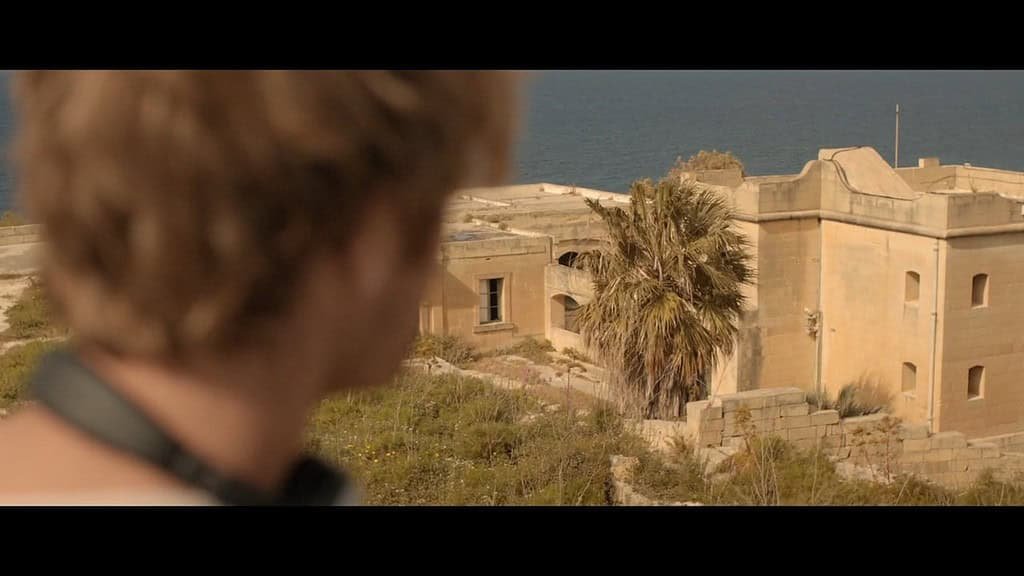 A man's head fills the left-hand side of the screen as he