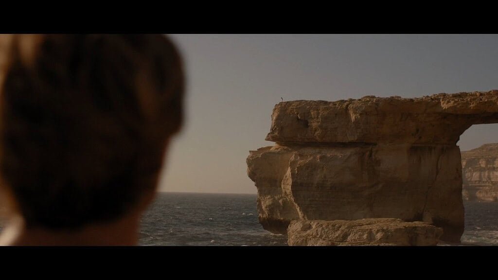 The back a man's head fills the left-hand side of the screen as he looks at the Azure Window.