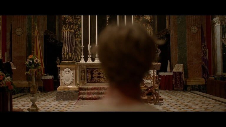 Person facing ornate church altar.