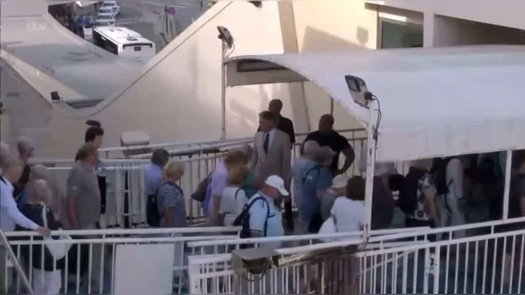 Passengers walking across a footbridge from a ferry to land.