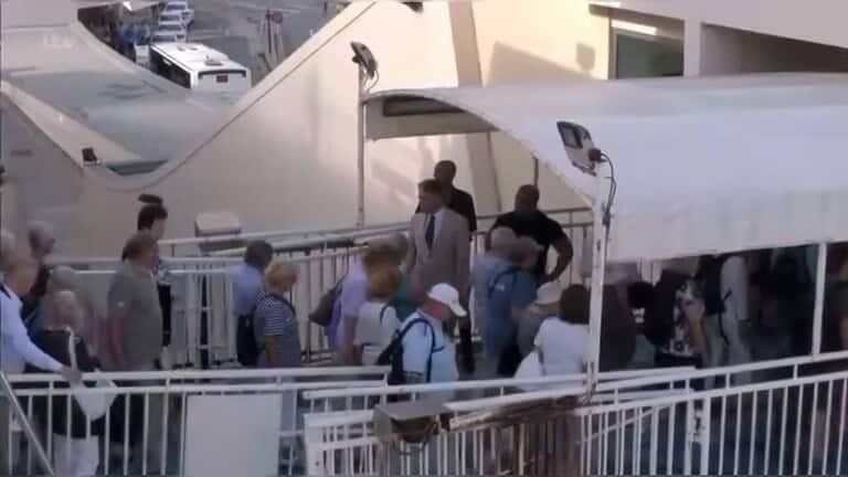 Passengers walking across a footbridge from a ferry to land.