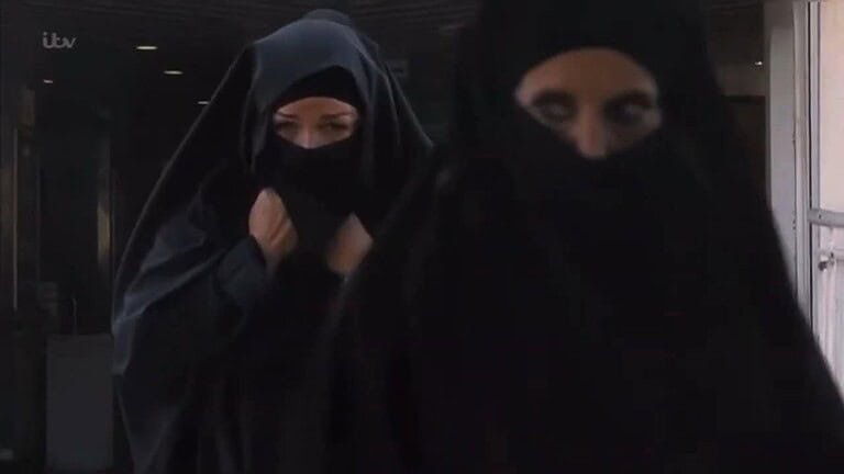 Two figures in black burhkas walking.