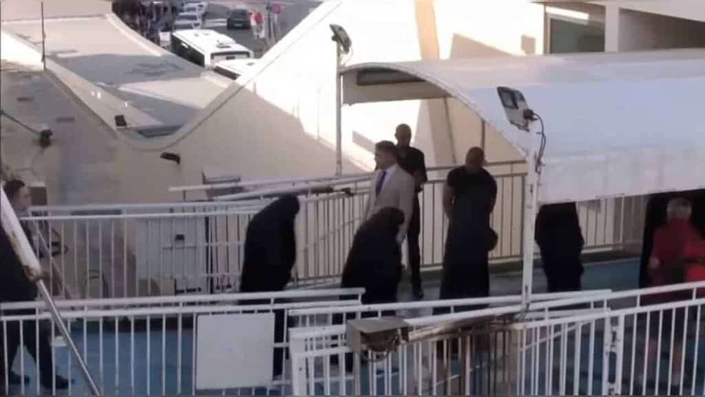 People gathered on a footbridge from a ferry to land.
