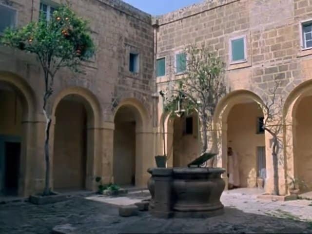 Ancient courtyard with stone arches and well, gozo Malta.