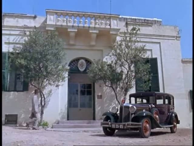 Vintage car parked in front of historic building in Gozo, Malta, scenic Mediterranean architecture.
