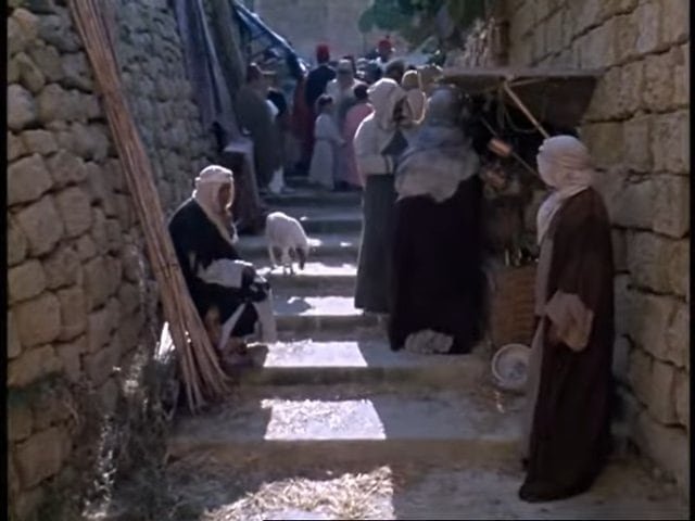 Vintage Mediterranean street scene in Gozo, Malta, showing local residents and traditional architecture.