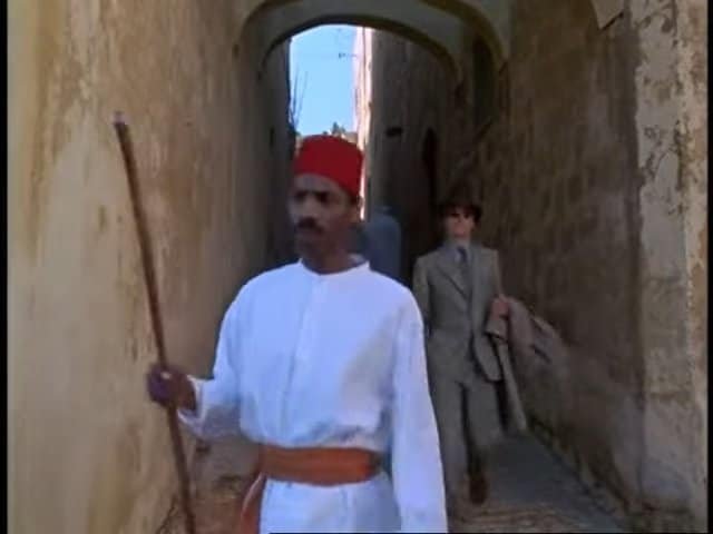 Colonial-era man walking through narrow alley in Gozo, Malta, historic street scene.
