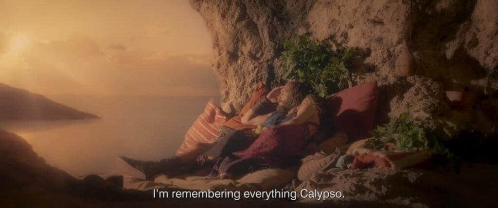 A couple resting against cushions in a serene cave, overlooking the sea.