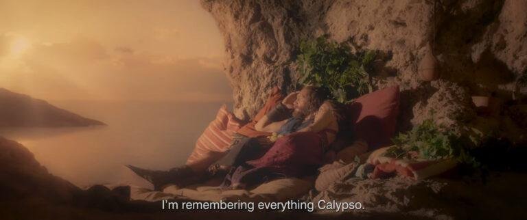 A couple resting against cushions in a serene cave, overlooking the sea.
