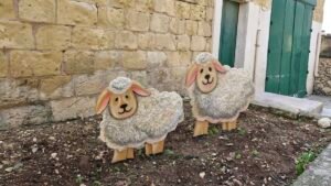 Two cheerful sheep decorations in garden.