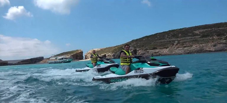 Two people riding jet skis on water.