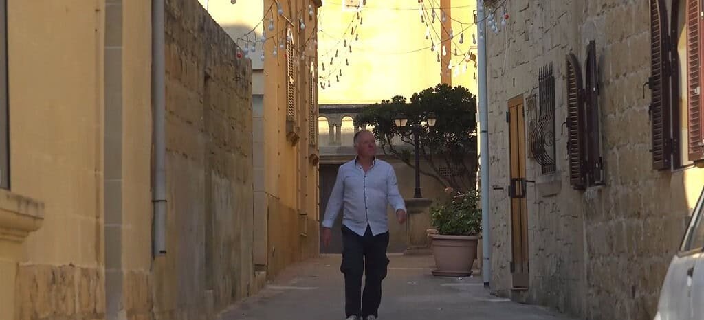 Man walking down a sunlit street.