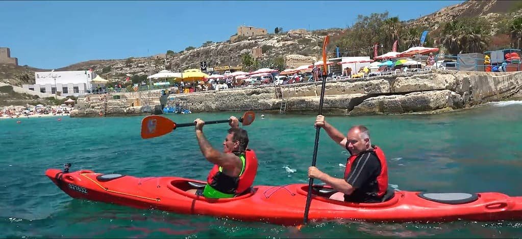 Two people kayaking in clear water.