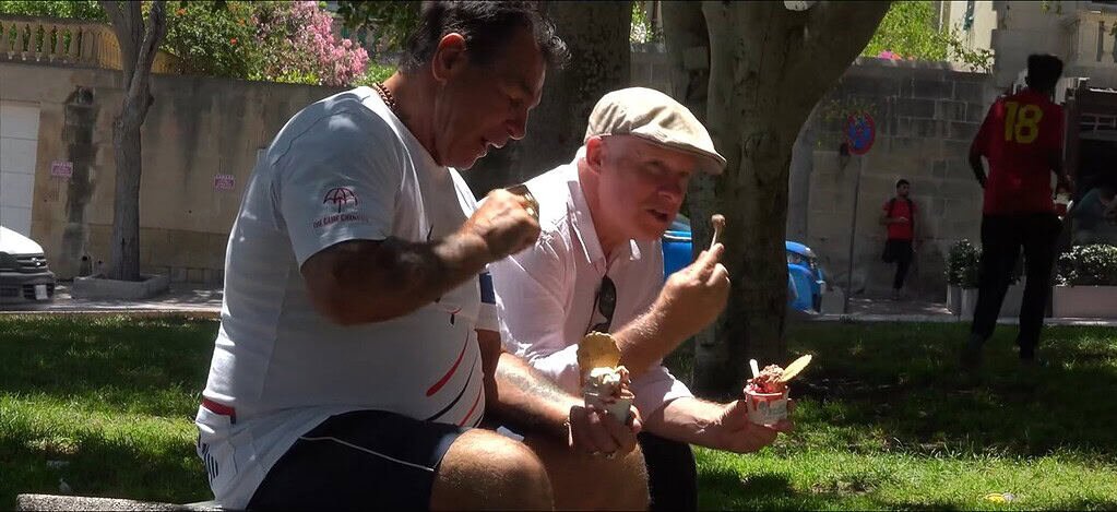 Two men enjoying ice cream outdoors.