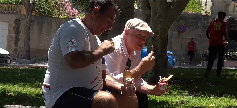 Two men enjoying ice cream outdoors.