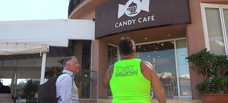 Man in neon shirt outside café.
