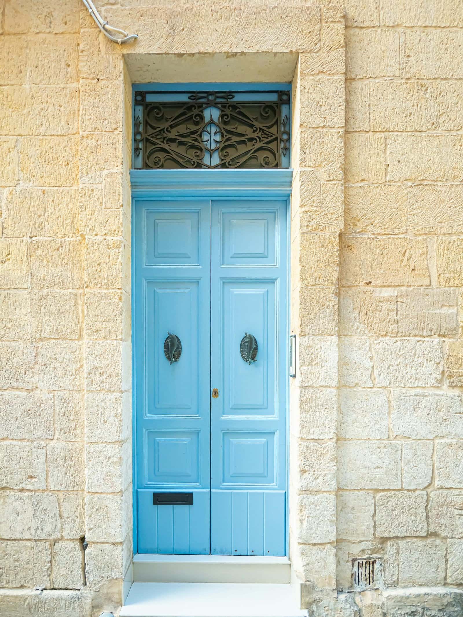 A traditional Mediterranean blue door set in a rustic stone wall in Malta, exuding historic charm.