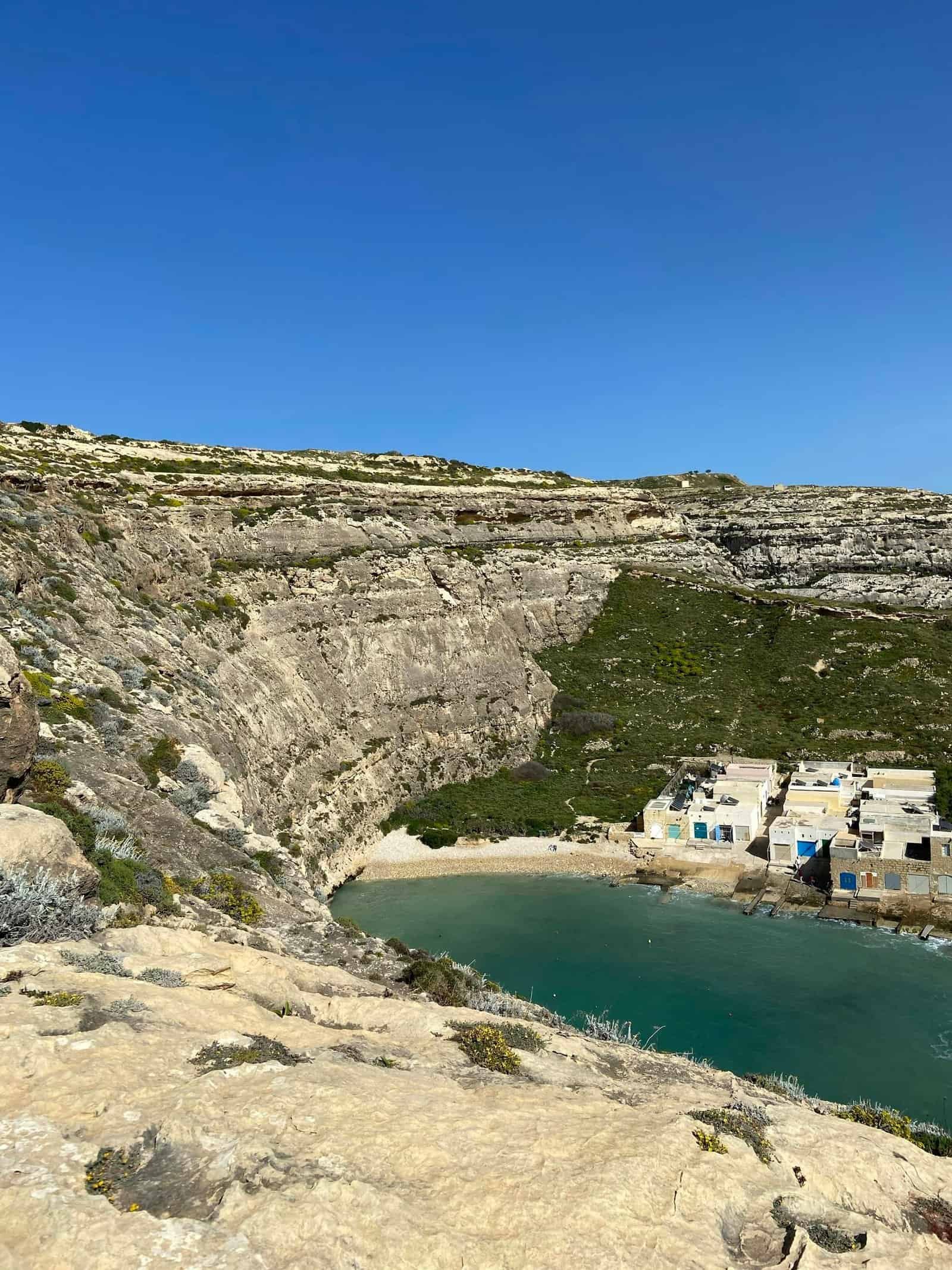 Beautiful cliffside view of a tranquil cove under a clear blue sky.